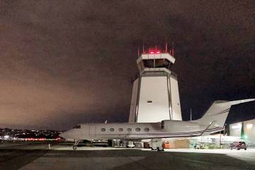 Business jet parked in front of air traffic control tower at Van Nuys Airport at night