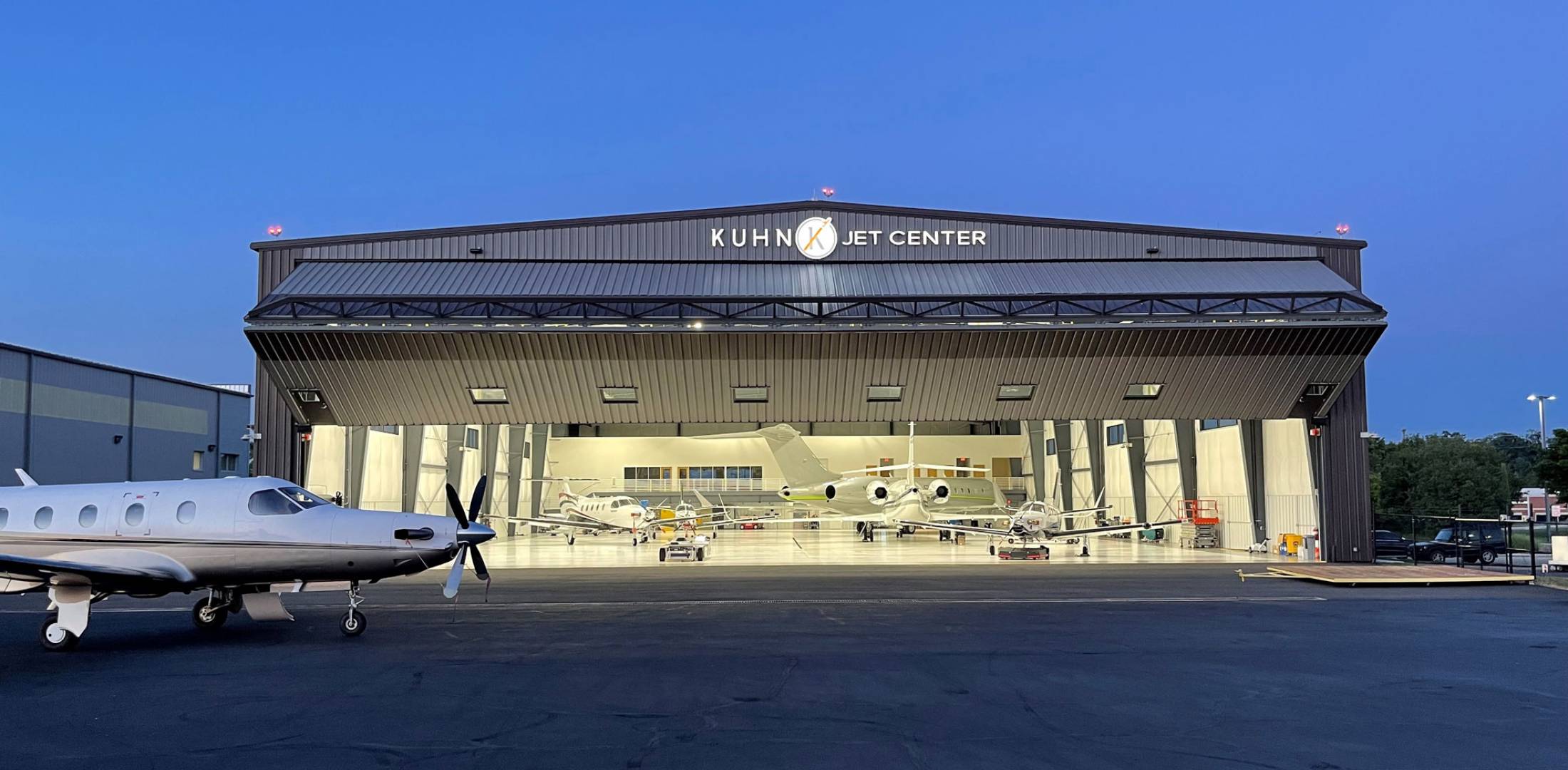 Kuhn Jet Center hangar at Leesburg Executive Airport illuminated at night with business aircraft parked inside