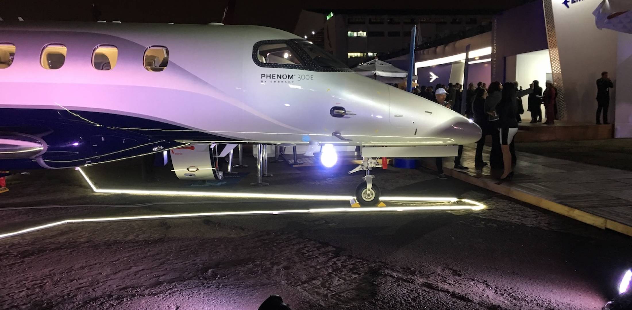 Embraer Phenom 300E on static display at 2018 LABACE show Congonhas Airport, San Paulo, Brazil illuminated at night and surrounded by event attendees