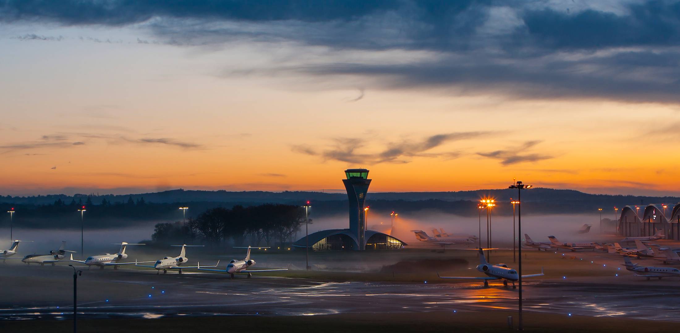 Business jets at Farnborough Airport shrouded with fog at dusk